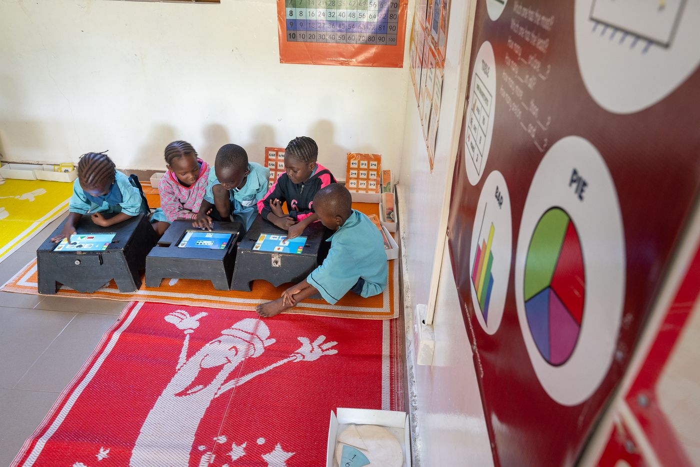 Children working at a maths station on tablets
